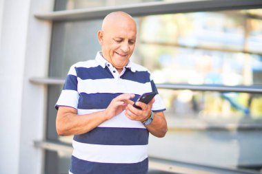 Kıdemli yakışıklı adam mutlu ve kendinden emin gülümsüyor. Yüzünde gülümsemeyle şehrin caddesinde akıllı telefon kullanarak dikiliyorsun.