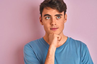 Teenager boy wearing casual t-shirt standing over blue isolated background serious face thinking about question, very confused idea