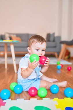 Anaokulunda küçük renkli toplarla oynayan güzel bir çocuk.