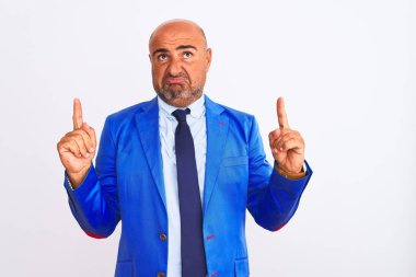 İzole edilmiş beyaz arka plan üzerinde duran orta yaşlı iş adamı üzgün ve üzgün görünüyor, parmaklarıyla yönü gösteriyor, mutsuz ve depresif..
