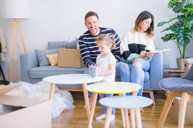 Karton kutular etrafında yeni evde kara tahta tutan kanepede oturan çocuk ile güzel famiily