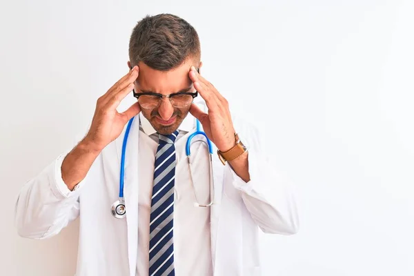 ストレスが原因で頭の痛みのために頭の上に手で孤立した背景に聴診器を身に着けている若いハンサムな医者の男 片頭痛に苦しむ — ストック写真