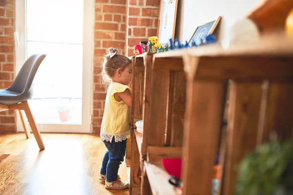 Schöne Kleinkind Steht Und Nimmt Spielzeug Aus Dem Regal Kindergarten — Stockfoto