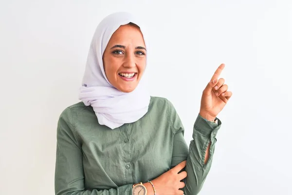 若いです美しいですアラブ女性身に着けています伝統的なイスラム教徒のヒジャーブ顔に大きな笑顔で隔離された背景に カメラを見て側に手と指で指して — ストック写真