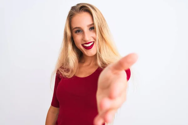 年轻美丽的女人穿着红色的T恤 站在孤独的白色背景上 微笑友好地握手致意和欢迎 成功的业务 — 图库照片