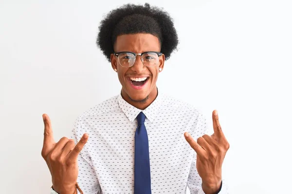 孤立した白い背景の上にネクタイと眼鏡をかけている若いアフリカ系アメリカ人ビジネスマンが手を上げて岩のシンボルをやって狂気の表情で叫んでいます 音楽スター 重い概念 — ストック写真