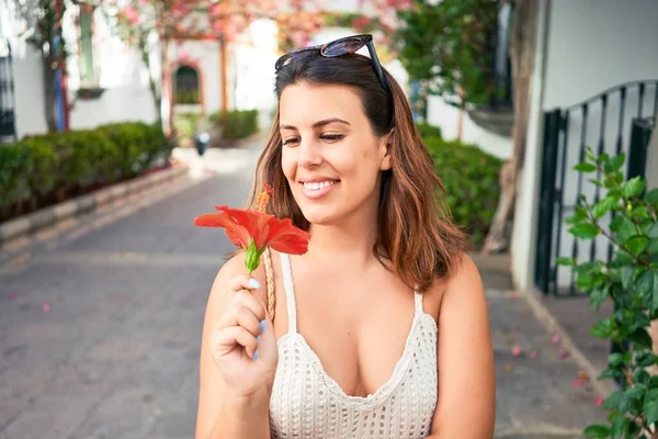 Young beautiful woman at the colorful village of Puerto de Mogan, smiling happy smelling flower on the street on summer holidays