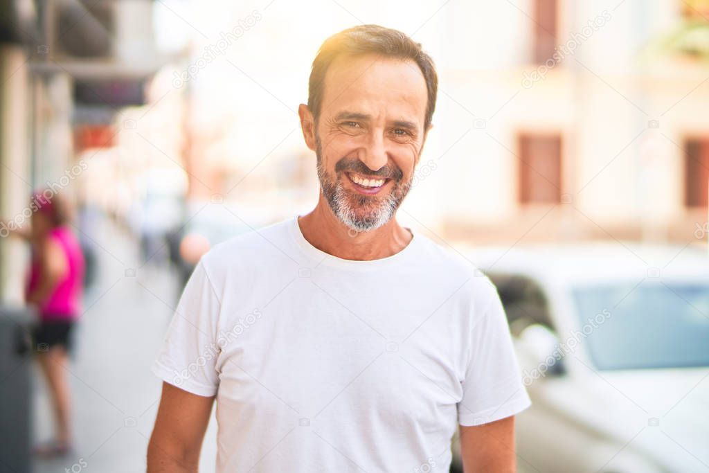 Middle age handsome man standing on the street smiling