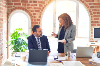 Two middle age business workers working together. Woman bullying man at the office clipart