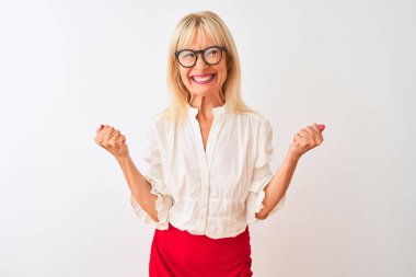 Orta yaşlı iş kadını gömlek ve gözlük takıyor. İzole edilmiş beyaz arka planda duruyor. Çok mutlu ve heyecanlı. Kutlama konsepti.