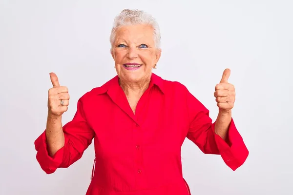 赤いカジュアルなシャツを着たシニアグレーの髪の女性は 孤立した白い背景の成功のサインの上に立って手で積極的なジェスチャーを行うと 親指を笑顔と幸せ 陽気な表情と勝者のジェスチャー — ストック写真