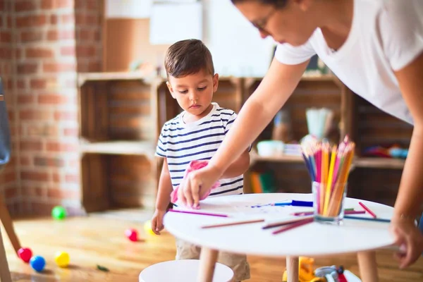 幼稚園で色鉛筆を使って絵を描く美しい先生と幼児 — ストック写真