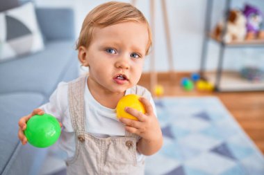 Sevimli sarışın çocuk anaokulunda bir sürü oyuncakla oynuyor.
