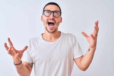 Gözlüklü genç yakışıklı bir adam izole arka planda duruyor. Deli gibi bağırıyor, bağırıyor, agresif bir ifade ve kollarla bağırıyor. Hayal kırıklığı konsepti.