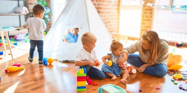 Güzel öğretmen ve bir grup çocuk anaokulunda bir sürü oyuncakla oynuyorlar.