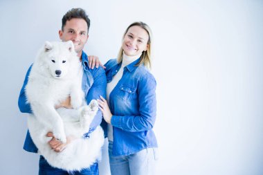 Genç güzel çift izole beyaz arka plan üzerinde duran köpek tutarak