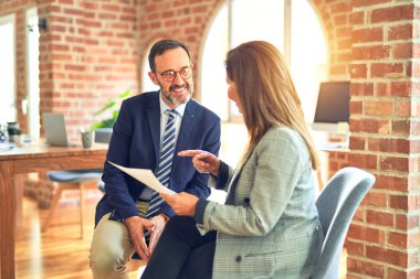 Mutlu ve kendinden emin gülümseyen iki orta yaşlı iş adamı. Ofisteki belgeleri okurken gülümseme ile birlikte çalışmak.