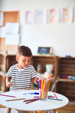 Güzel çocuk anaokulunda renkli kalemler kullanarak sevimli bir çizim yapıyor.