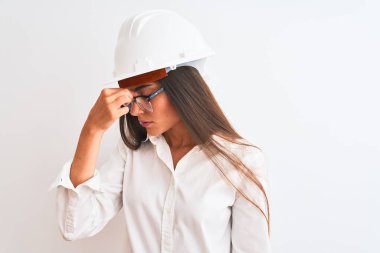 İzole edilmiş beyaz arka planda kask ve gözlük takan genç, güzel bir mimar. Burnu ve gözleri ovuşturmaktan yorgun düşmüş ve başı ağrıyormuş. Stres ve hüsran kavramı.