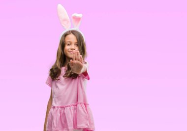 Esmer Latin kız açık eliyle dur işareti ile ciddi ve kendine güvenen ifade, savunma jest yapıyor Paskalya tavşan kulakları giyiyor