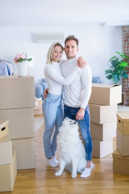Karton kutular etrafında yeni evde duran köpek ile genç güzel çift