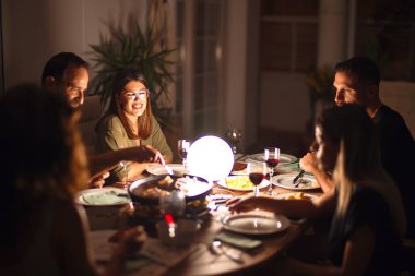 Güzel bir aile akşam yemeğinde terasta konuşuyor ve gülümsüyor