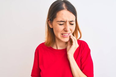 Beautiful redhead woman wearing casual red t-shirt over isolated background touching mouth with hand with painful expression because of toothache or dental illness on teeth. Dentist concept.