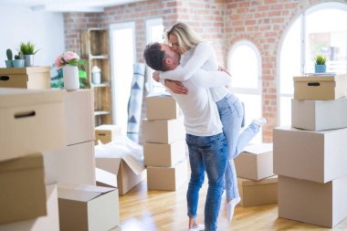 Karton kutular etrafında yeni evde sarılma genç güzel çift