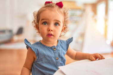Renkli oyun odasında beyaz güzel bir bebek oyuncaklarla oynuyor. Anaokulunda renkli kalemlerle mutlu ve eğlenceli çizimler..