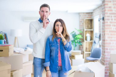 Genç ve güzel bir çift, yeni evlerinde karton kutuların etrafında durup parmakları dudaklarında sessiz olmak istiyorlar. Sessizlik ve gizli konsept.