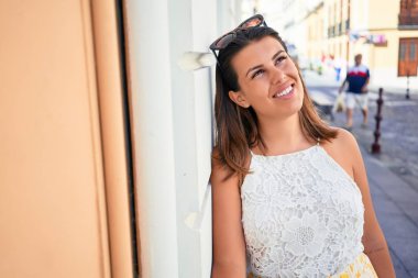 Turuncu duvara yaslanan güzel kız, güneşli bir yaz gününde gülümseyen genç arkadaş.