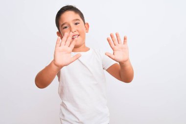Güzel çocuk, izole edilmiş beyaz arka planda dikilmiş tişört giyiyor. Korkudan dehşete düşmüş ve korkmuş. El hareketlerini durdur, şok içinde bağır. Panik konsepti.