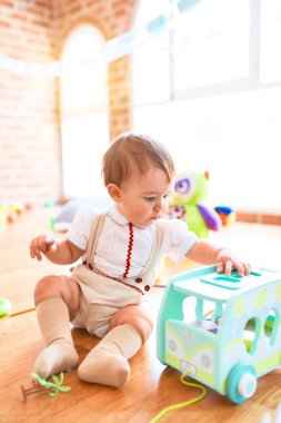 Anaokulunda bir sürü oyuncakla oynayan sevimli bir çocuk.