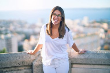 Mutlu ve kendinden emin gülümseyen genç ve güzel bir kadın. Kasaba caddesinde yüzünde gülümsemeyle dikilirken