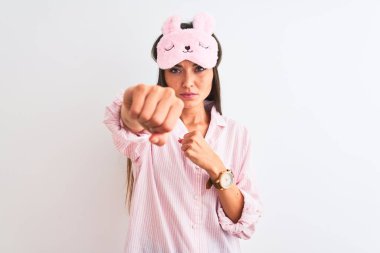 İzole edilmiş beyaz arka plan üzerinde uyku maskesi ve pijama giyen genç güzel bir kadın. Yumruk yumruğa dövüşmek, agresif ve öfkeli saldırı, tehdit ve şiddet.
