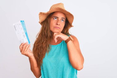 Orta yaşlı, olgun bir turist kadının izole edilmiş arka planda biniş kartı tutması. Ciddi bir yüz ifadesi. Soru sormayı düşünmek, kafa karıştırıcı bir fikir.