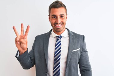 Takım elbiseli ve kravatlı genç yakışıklı iş adamı, kendinden emin ve mutlu gülümserken üç numaralı parmaklarıyla onu gösteriyor ve işaret ediyor..