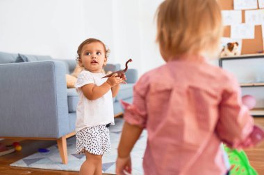 Anaokulunda bir sürü oyuncakla oynayan sevimli çocuklar.