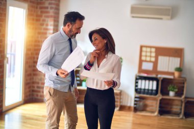 Mutlu ve kendinden emin gülümseyen iki orta yaşlı iş adamı. Yüzünde gülümsemeyle büroda belgeleri tutarak birlikte çalışıyoruz.