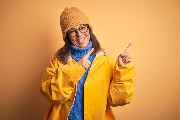 Middelbare Leeftijd Vrouw Met Gele Regenjas Winterhoed Geïsoleerde Achtergrond Glimlachend — Stockfoto