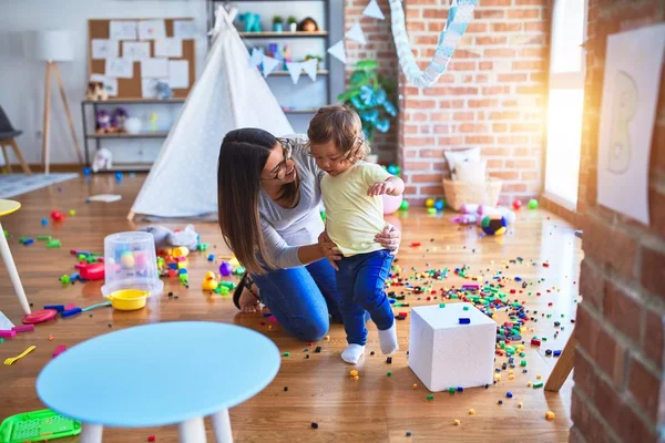 Anaokulunda oynayan genç ve güzel öğretmen ve bebek.