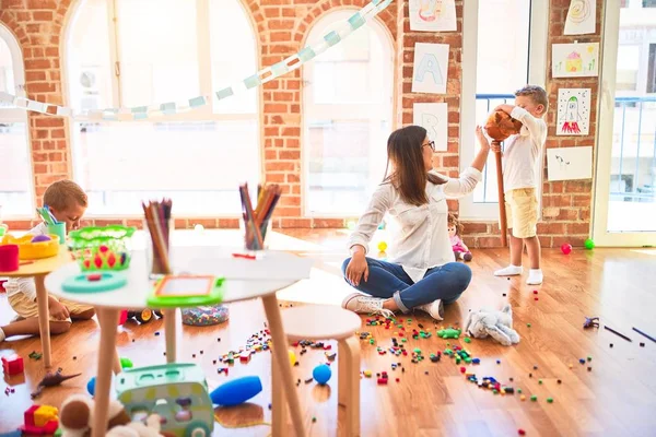 Hermosa Maestra Niños Pequeños Jugando Alrededor Montón Juguetes Jardín Infantes — Foto de Stock