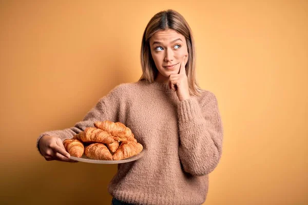 Young Beautiful Woman Holding Plate Croissants Isolated Yellow Background Serious — Stock Photo, Image