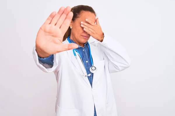 中年成熟的医生妇女戴听诊器 双手捂住眼睛 用悲伤和恐惧的表情做停止动作 尴尬和消极的概念 — 图库照片