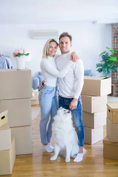 ダンボール箱の周りに新しい家に立っている犬を持つ若い美しいカップル — ストック写真