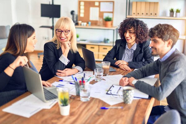 Group of business workers smiling happy and confident. Working together with smile on face  using laptop and speaking at the office
