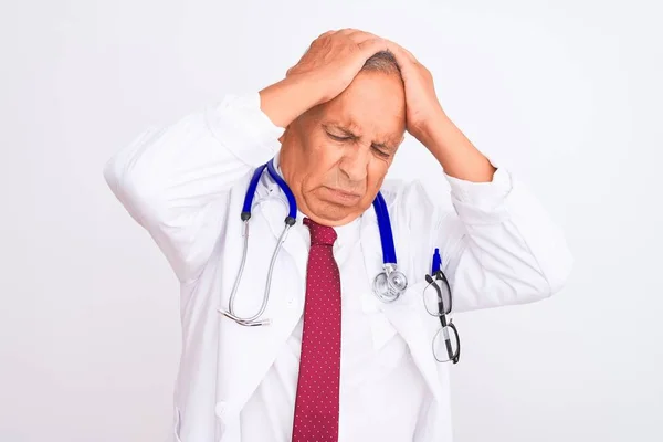 年长白发苍苍的医生男子穿着听诊器站在孤立的白色背景上 头痛绝望 压力大 因为疼痛和偏头痛 手放在头上 — 图库照片