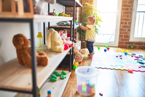 Красивий Малюк Стоїть Приймаючи Іграшки Стелажів Дитячому Саду — стокове фото