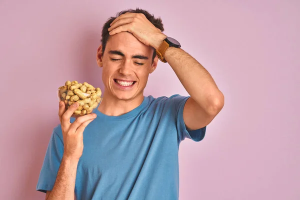 Menino Adolescente Segurando Monte Amendoins Sobre Fundo Rosa Isolado Estressado — Fotografia de Stock