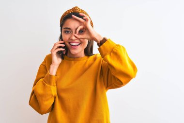 Akıllı telefondan konuşan güzel bir kadın mutlu bir yüzü olan, izole edilmiş beyaz bir arka planda duruyor.